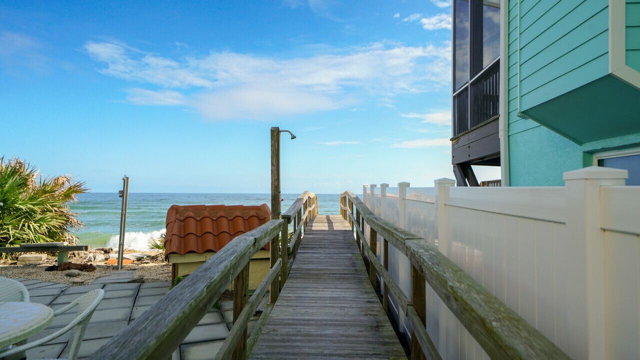 En träpromenad som leder till en strand med utsikt över havet.
