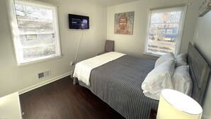 Une chambre à coucher avec un lit, un téléviseur fixé au mur et un tableau représentant un Bouddha.