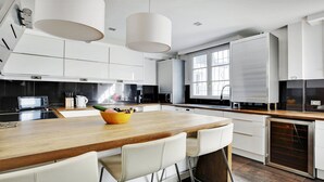 Een moderne keuken met witte kastjes, een houten kookeiland en een inbouwvaatwasser.