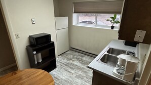 A compact kitchen with a microwave, refrigerator, sink, and a small window. - Cozy Bach Suite  (Winifred)