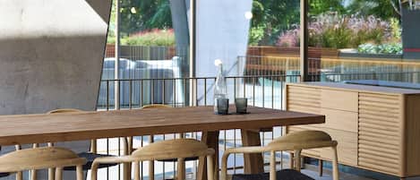 A modern dining area with a long wooden table, four chairs, and hanging pendant lights.