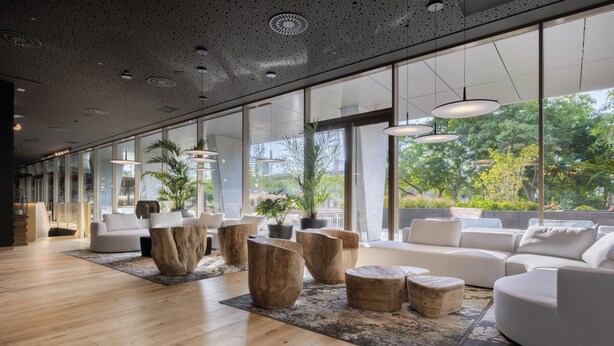 Un vestíbulo amplio con suelo de madera, sofás blancos y grandes ventanales que ofrecen vistas al exterior.