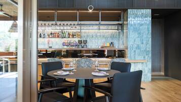 A modern restaurant with a bar area, multiple seating options, and a view of the outdoors.