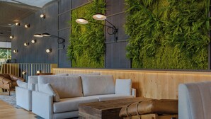 Un interior moderno con un sofá, una mesa de centro de madera y una pared decorada con plantas verticales.
