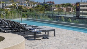 A rooftop pool area with lounge chairs, a circular seating area, and a view of the cityscape in the background. - Hotel SB Win 4 Sup (Sant Feliu de Llobregat)