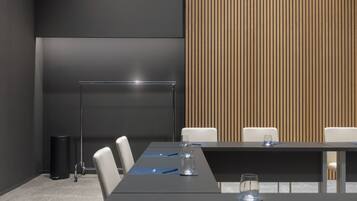 A conference room with a long table, white chairs, and a podium.