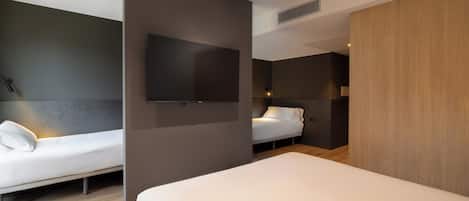 Una habitación de hotel moderna con dos camas, un televisor de pantalla plana y un armario de madera.