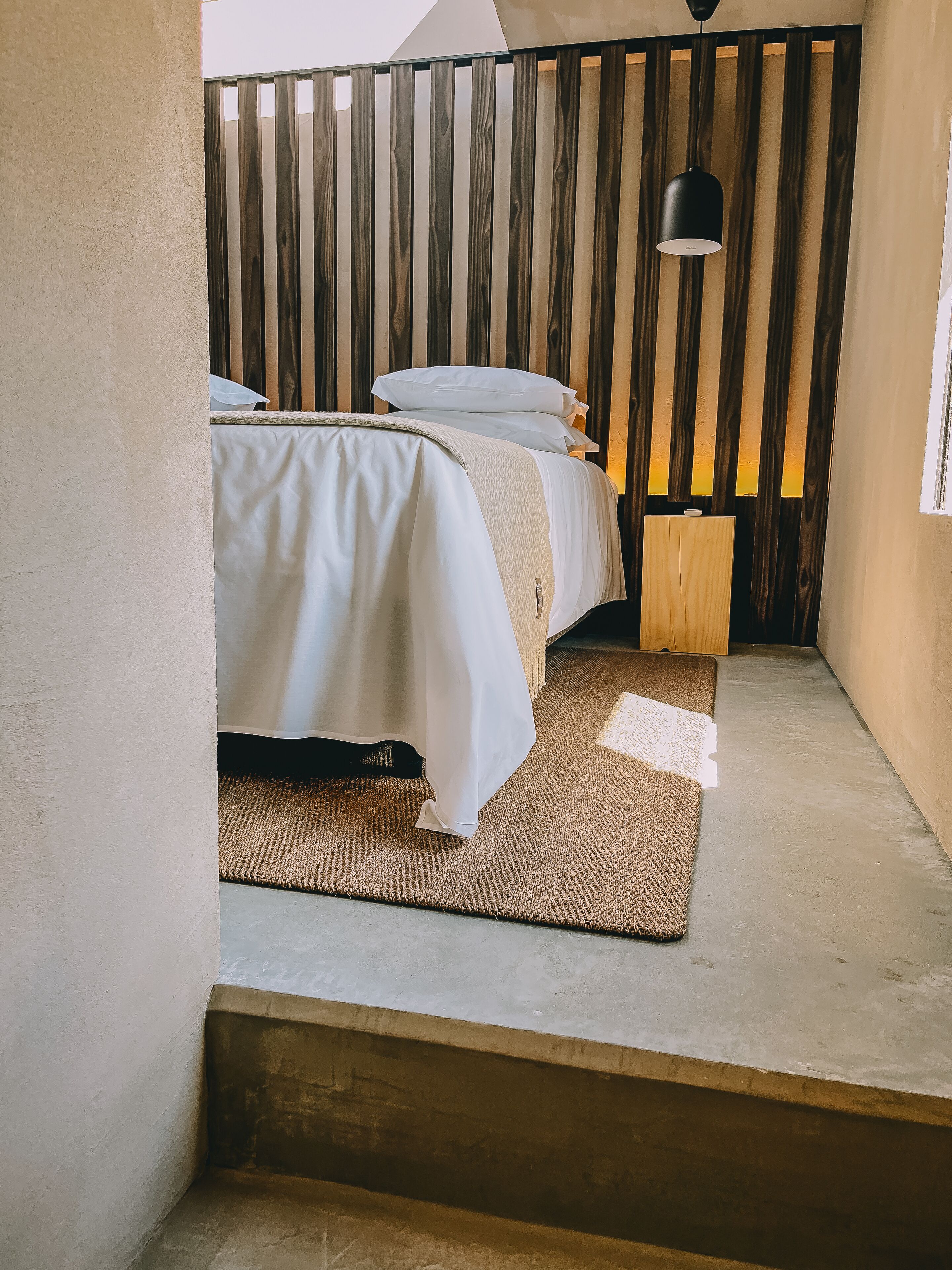 Une chambre à coucher avec un lit, une table de chevet et un luminaire suspendu.