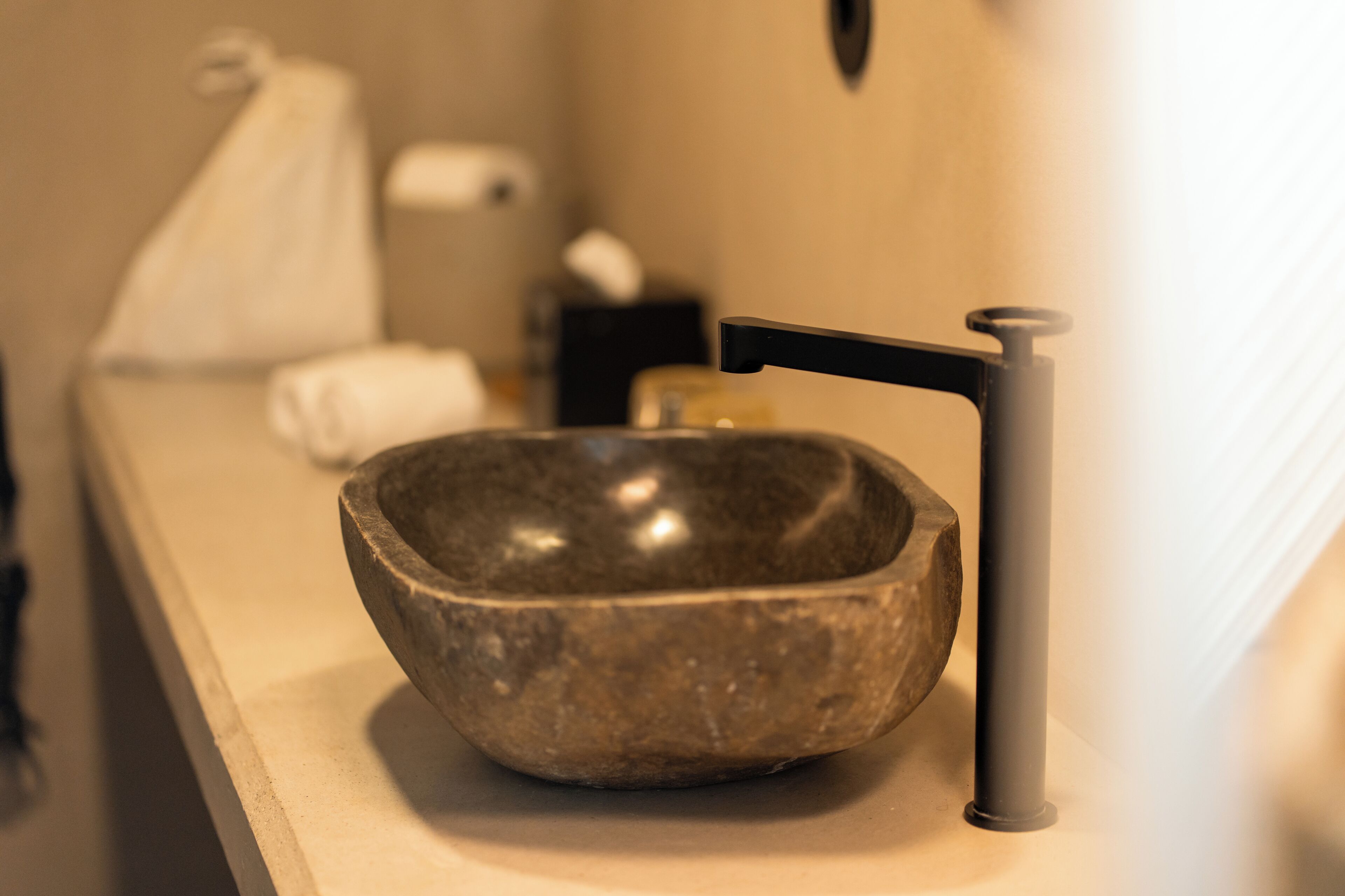 Ein Waschbecken aus Stein mit einem modernen Wasserhahn in einem Badezimmer.