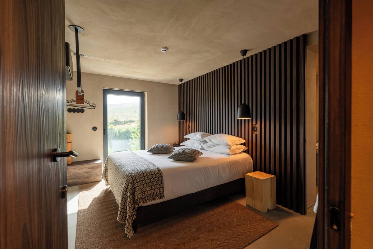 Une chambre avec un grand lit, des tables de chevet, une fenêtre et une vue sur l’extérieur.