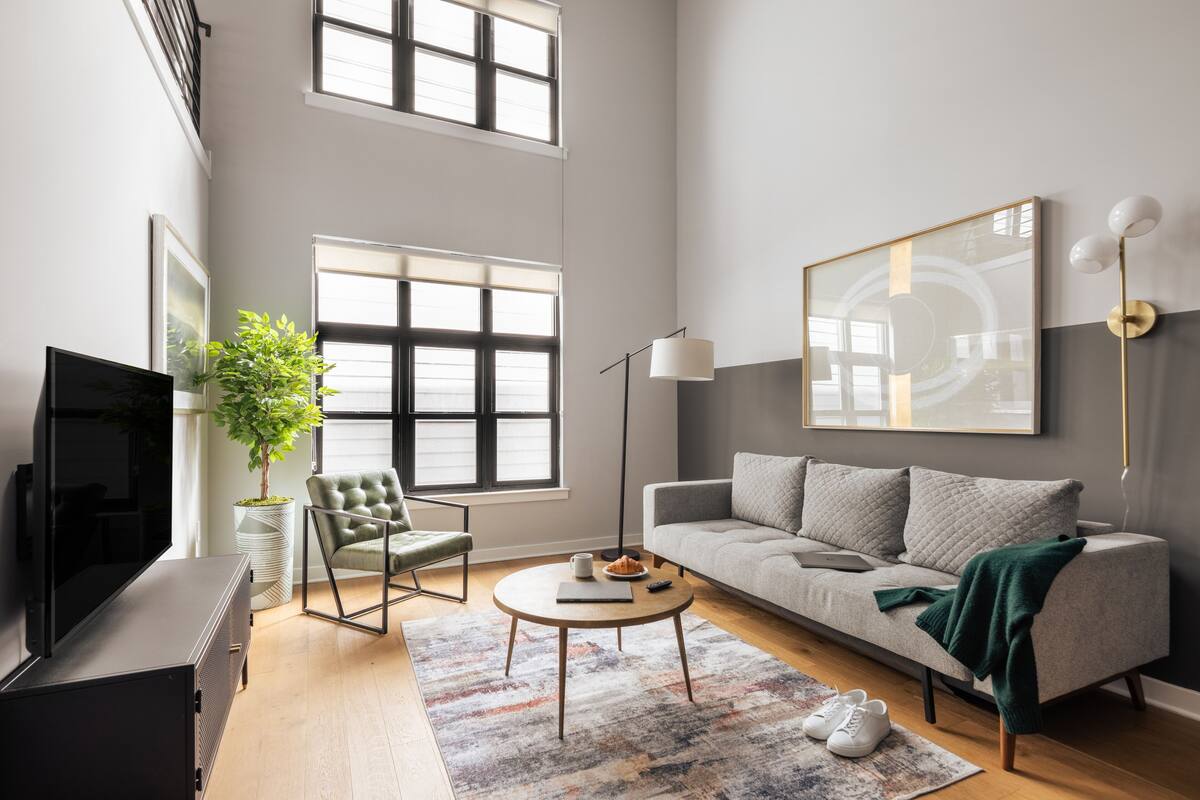 Ein modernes Wohnzimmer mit einer Couch, einem Couchtisch, einem Fernseher und einer Stehlampe.