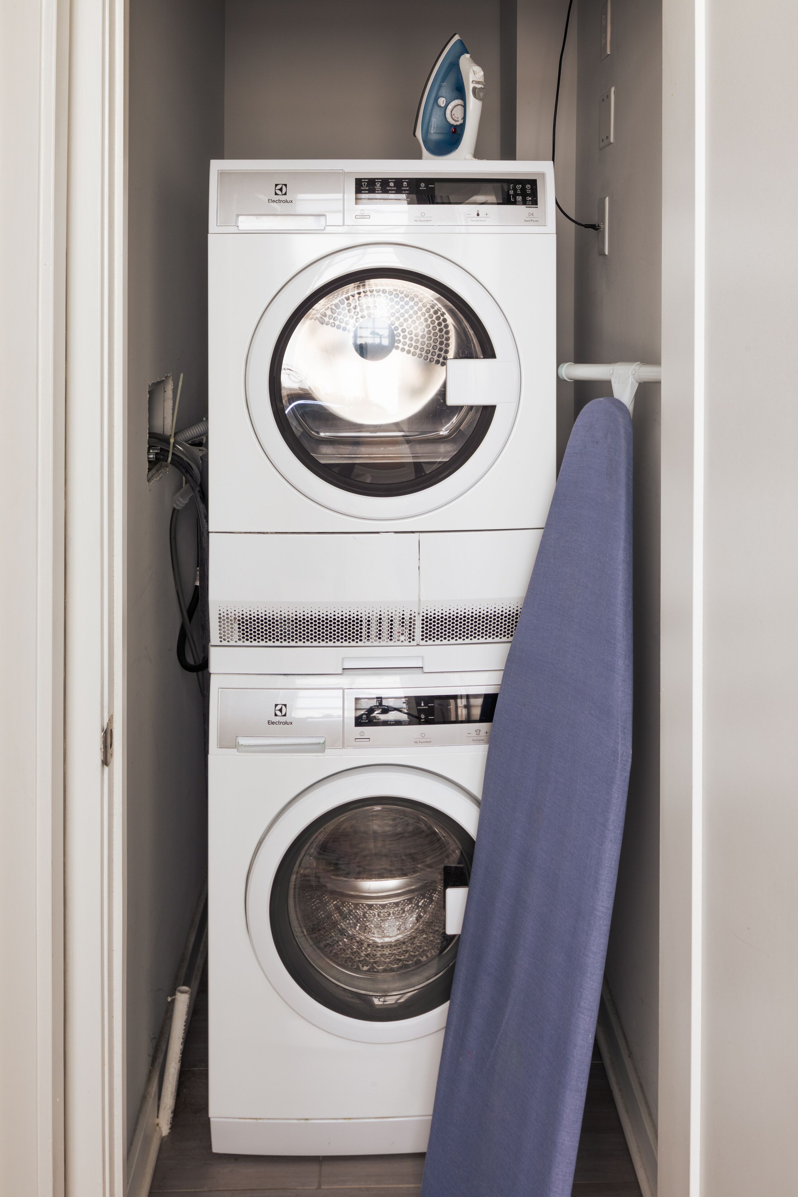 A compact, two-door washing machine with a control panel and a blue iron on top.