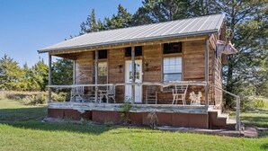 Eine rustikale Holzhütte mit Veranda, einer Tür und einer kleinen Treppe, die zum Eingang führt.