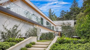 A modern house with a white exterior, wooden beams, and a glass facade.