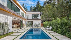 A modern house with a swimming pool, a patio with outdoor furniture, and a well-maintained garden.