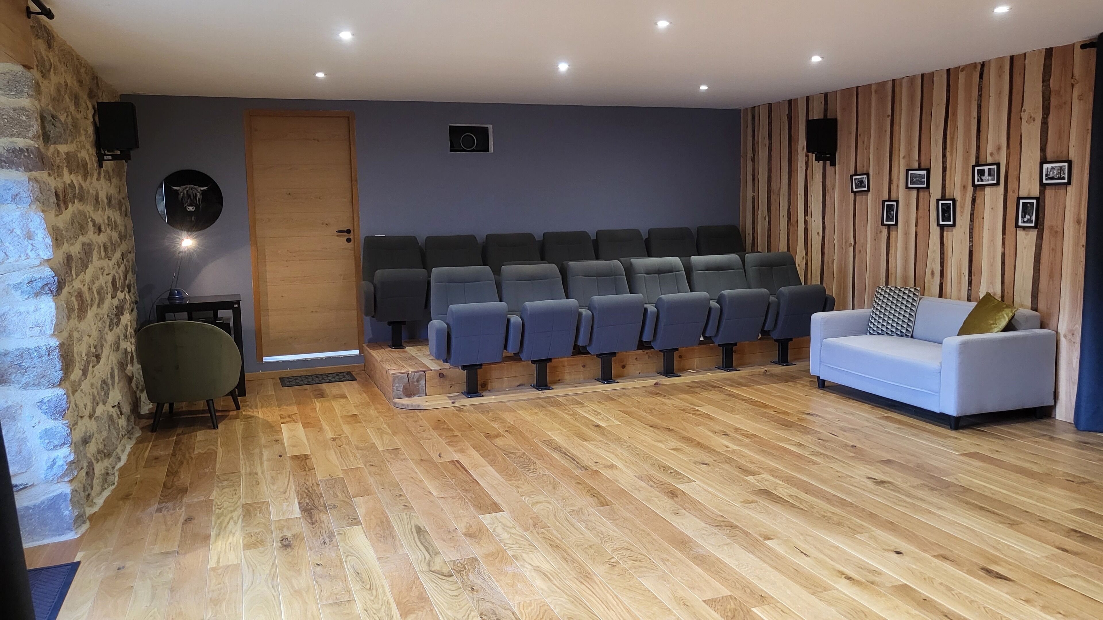 A room with a seating area, a door, a wall-mounted speaker, and a sofa.