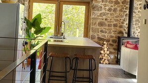 Una cocina rústica con pared de piedra, vigas de madera y un ventanal grande.