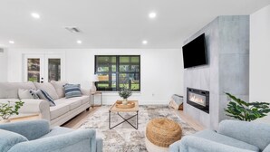 A modern living room with a sofa, armchairs, a coffee table, and a fireplace.