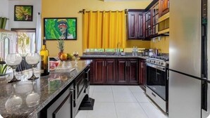 A kitchen with dark wooden cabinets, a stainless steel refrigerator, and a granite countertop.
