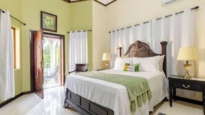 A bedroom with a bed, two bedside lamps, a nightstand, a door leading outside, and a window with curtains.