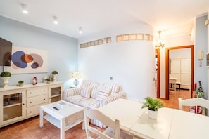 Een moderne woonkamer met een bank, eettafel en kasten.