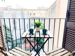 A balcony with a small table, two cups, and a potted plant.