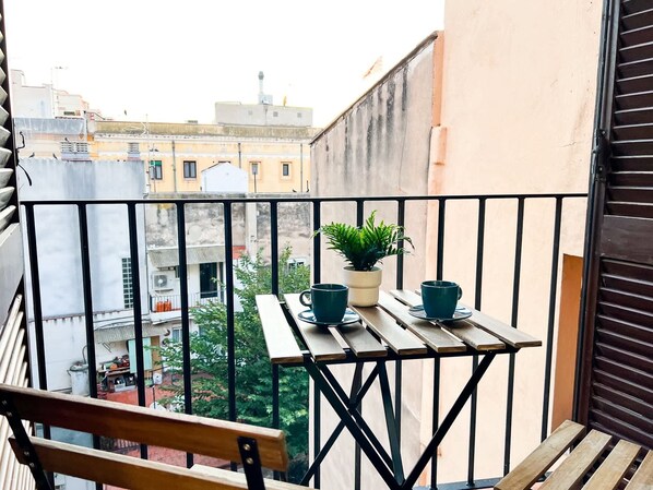 A balcony with a wooden table, two cups, and a potted plant.