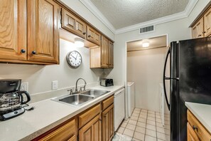 A kitchen with wooden cabinets, a stainless steel sink, a coffee maker, a toaster, and a refrigerator. - I24 - Apt|Patio|11mi to Convention Ctr|Sleeps 2 (Irving)