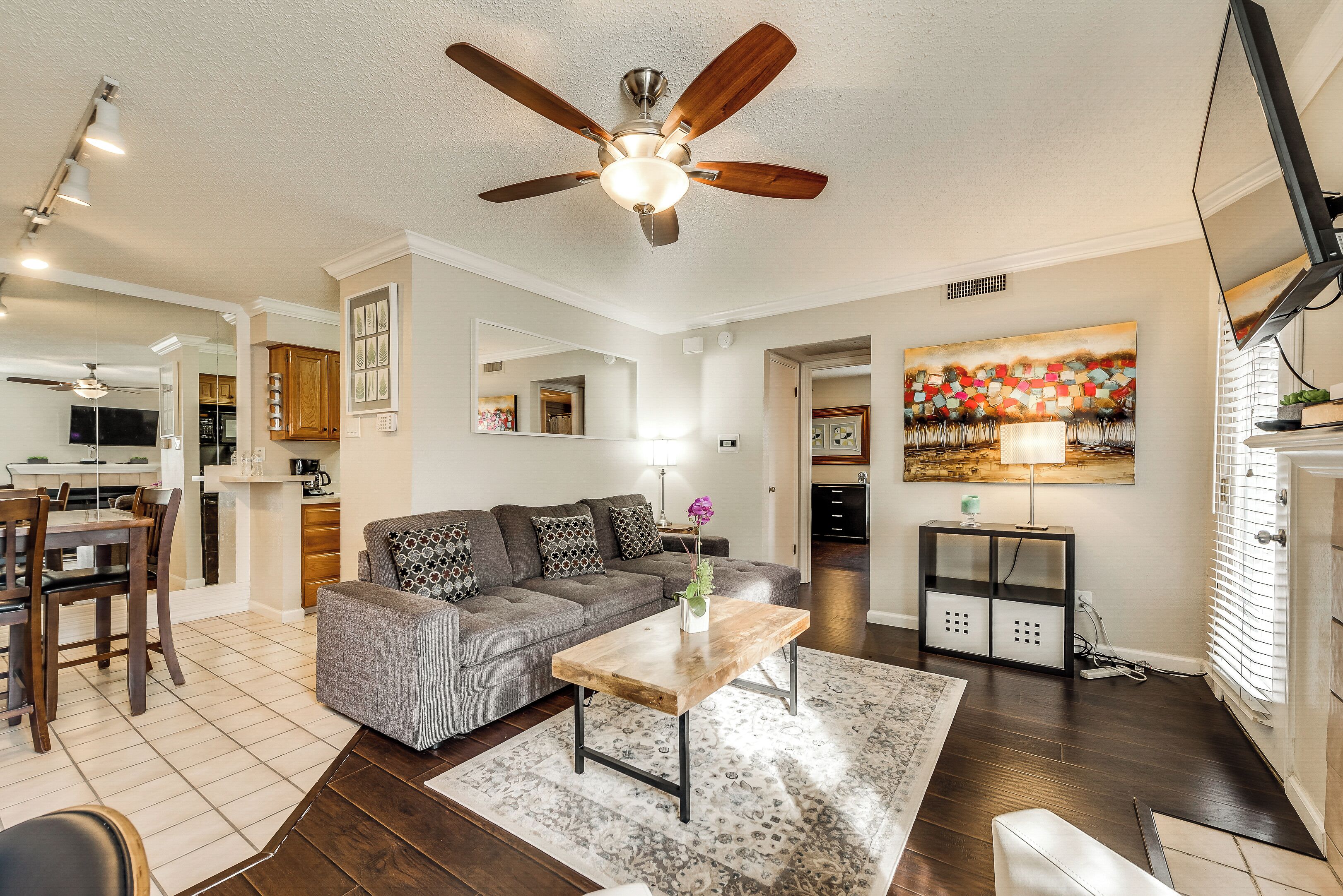 A modern living room with a gray sofa, wooden coffee table, and a ceiling fan.