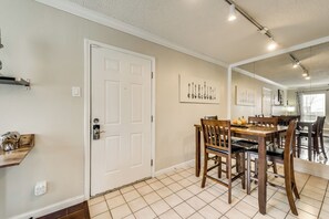 A dining area with a wooden table and chairs, a white door with a key lock, and a wall-mounted light fixture.