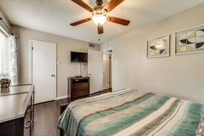 A bedroom with a bed, a ceiling fan, a TV, and a dresser.