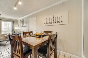 A dining area with a table set for four, a fruit bowl, and a wall art piece above the table. - I24 - Apt|Patio|11mi to Convention Ctr|Sleeps 2 (Irving)