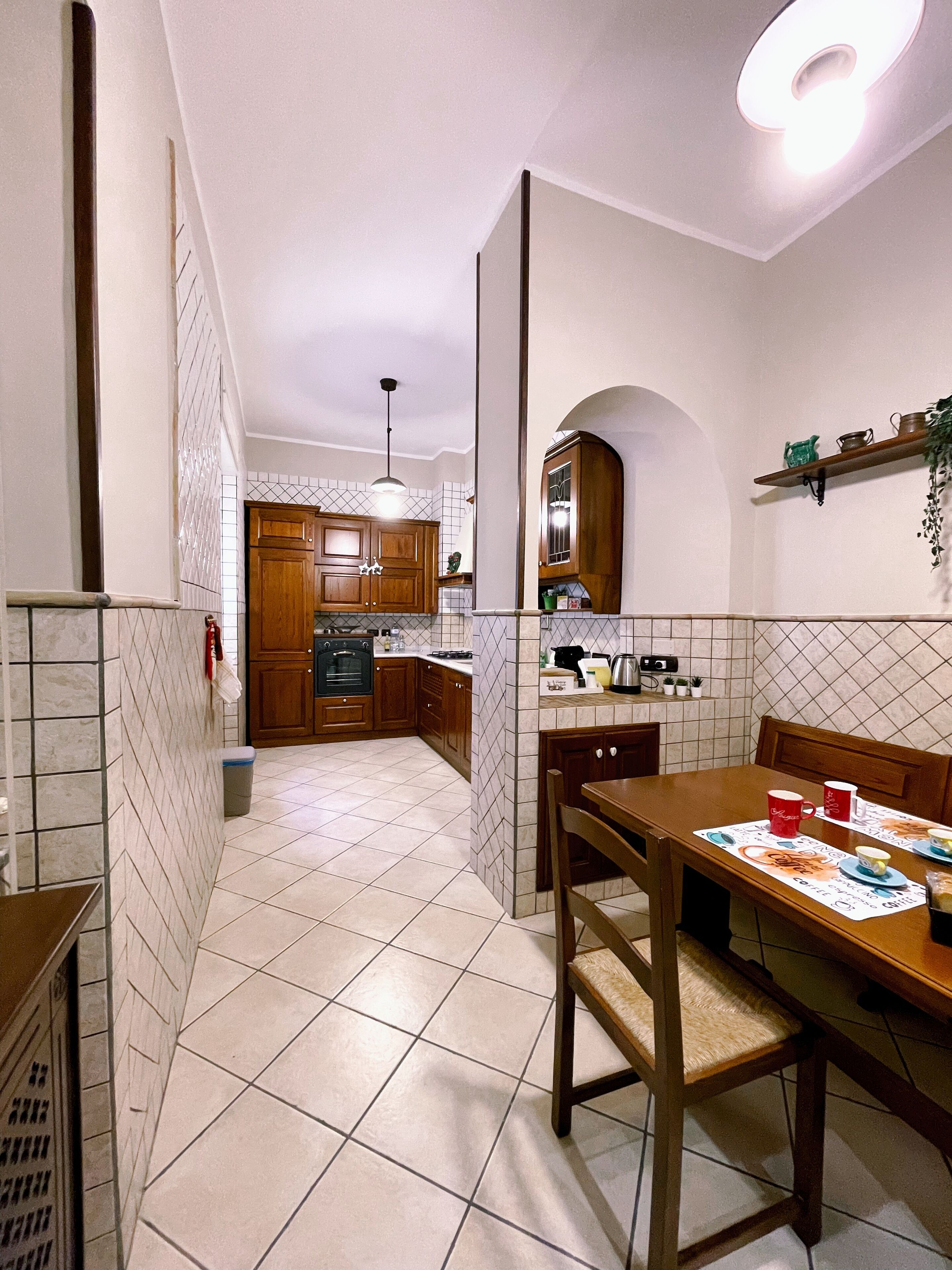 Una cocina con armarios de madera, salpicadero de azulejos y un comedor con mesa y sillas.