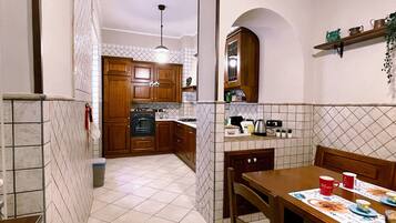 Una cocina con armarios de madera, salpicadero de azulejos y un comedor con mesa y sillas.
