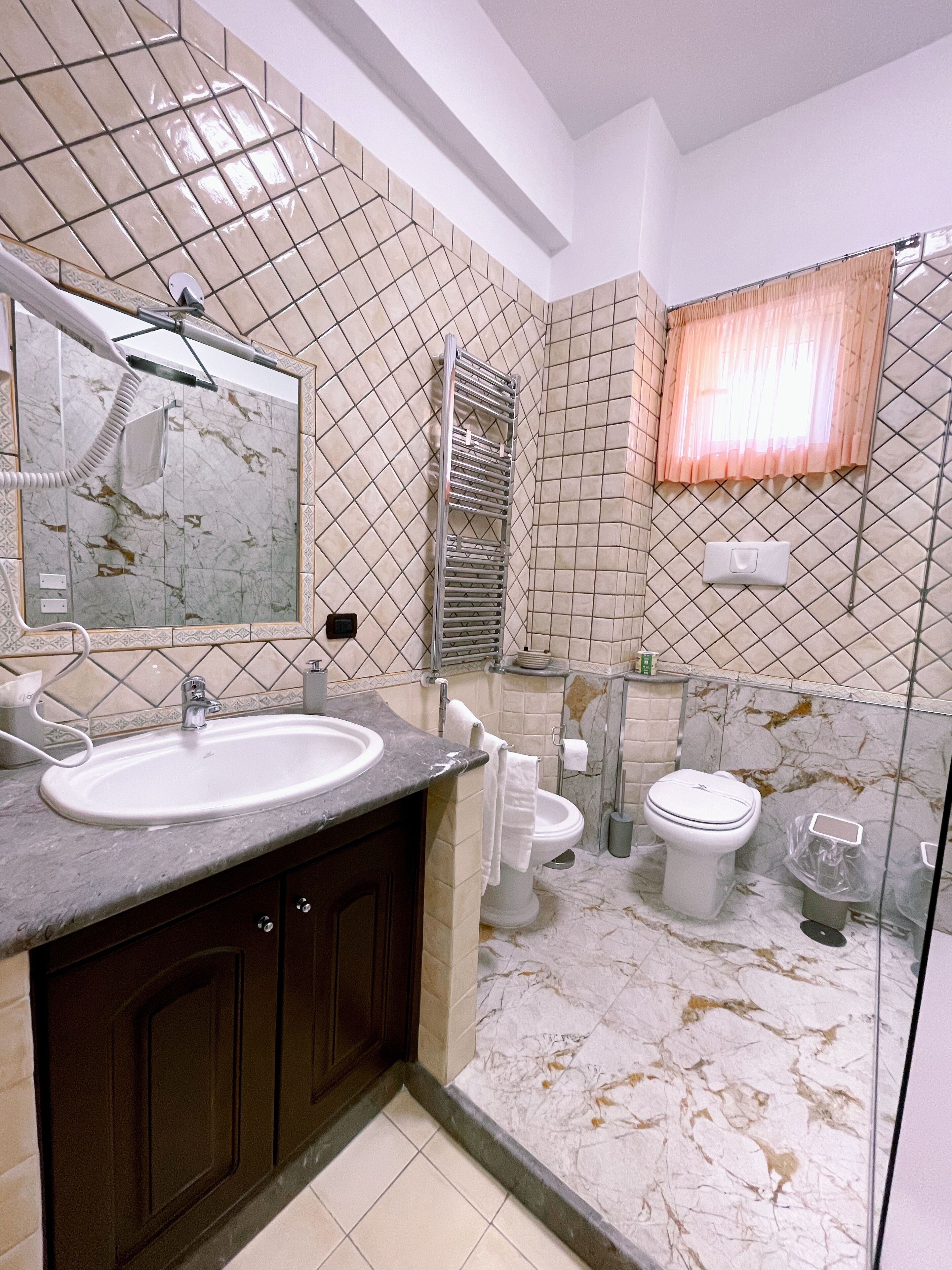 A bathroom with a marble sink, a glass shower enclosure, and a toilet.