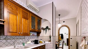 A modern kitchen with wooden cabinets, a double sink, and a tiled backsplash. - Oasi d'Oltremare (Naples)