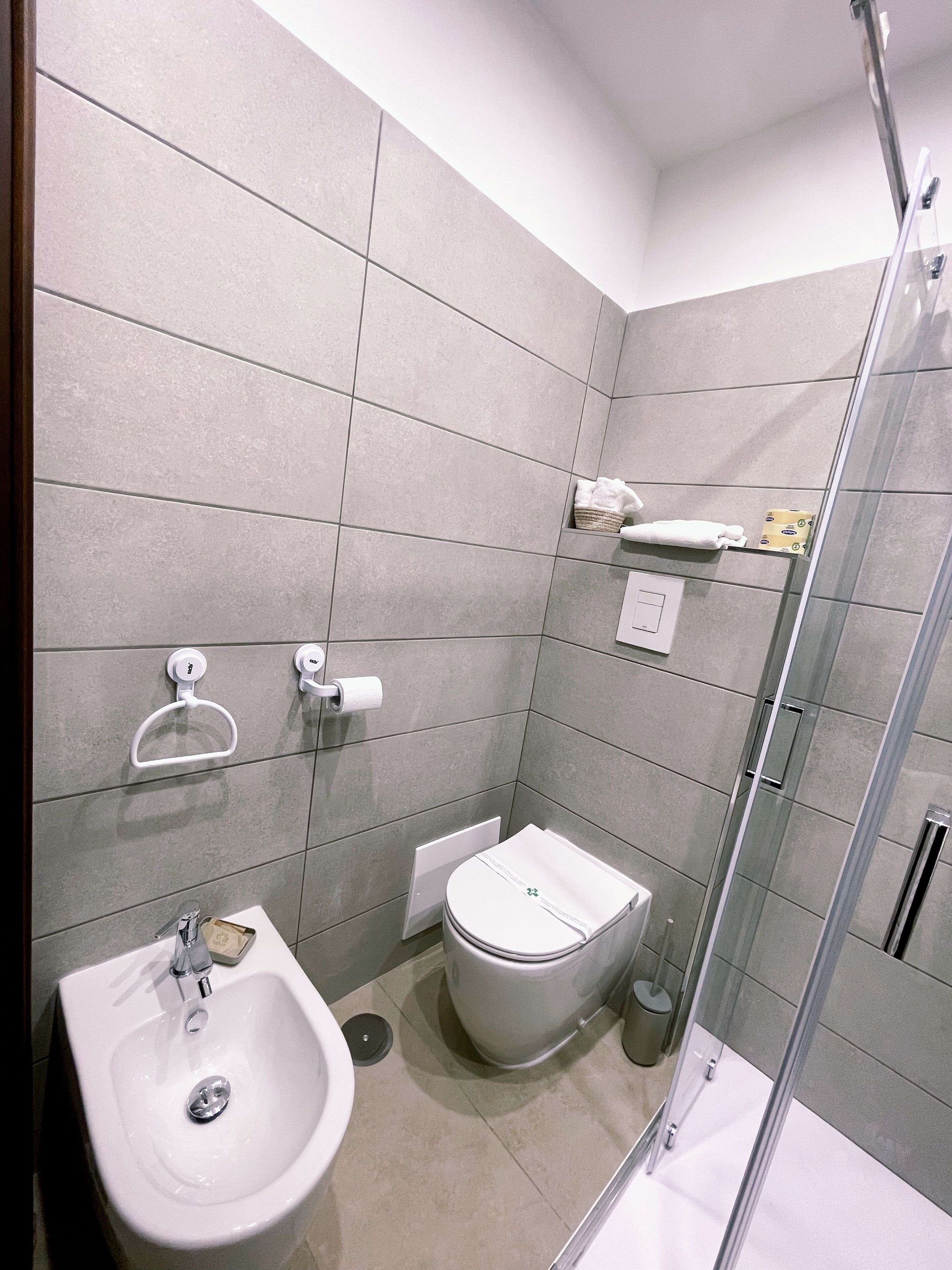 A modern bathroom with a bidet, a toilet, and a glass shower enclosure.
