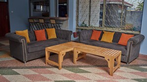 Ein Wohnzimmer mit zwei grauen Sofas, orangefarbenen Kissen und einem Holztisch.