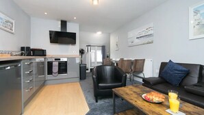 A modern kitchen with a microwave, oven, and a dining area with a table and chairs. - Self Contained Apartment at Country Pub Restaurant - Pass the Keys (Llanddona)
