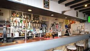 A bar area with multiple beer taps, a counter, stools, and a stone wall. - Self Contained Apartment at Country Pub Restaurant - Pass the Keys (Llanddona)