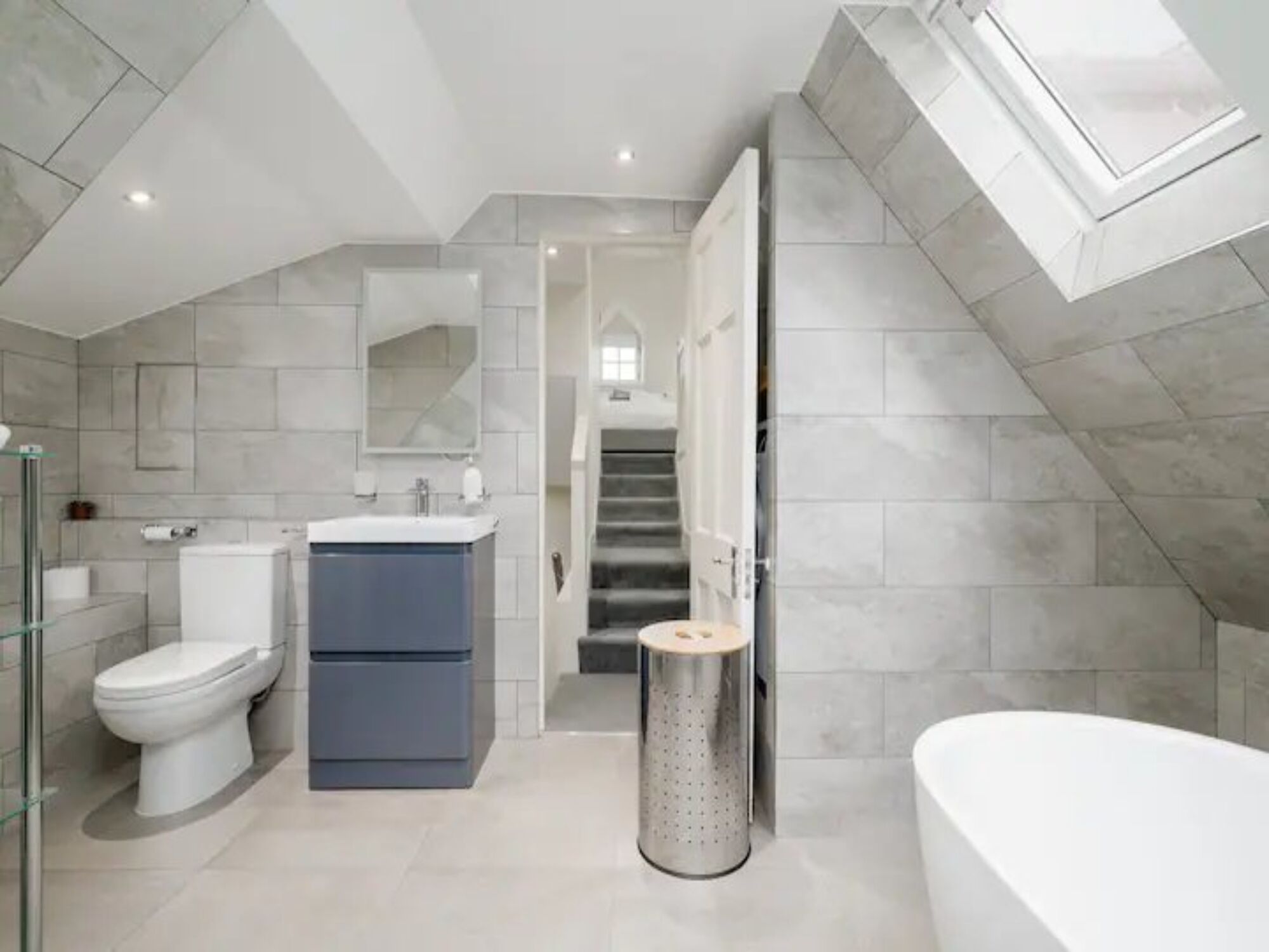 Een moderne badkamer met toilet, wastafel en bad.