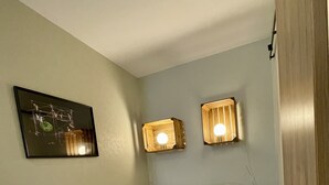 A neatly made bed with rolled towels, a framed artwork on the wall, and two wall-mounted lights. - Studio apartment  in Verdun, "Les Coulisses" (Verdun)