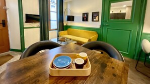 A dining table with a tray containing plates and cups, a yellow sofa, and a green door. - Studio apartment  in Verdun, "Les Coulisses" (Verdun)