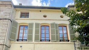 A two-story building with a beige facade, green shutters, and a wooden door. - Studio apartment  in Verdun, "Les Coulisses" (Verdun)