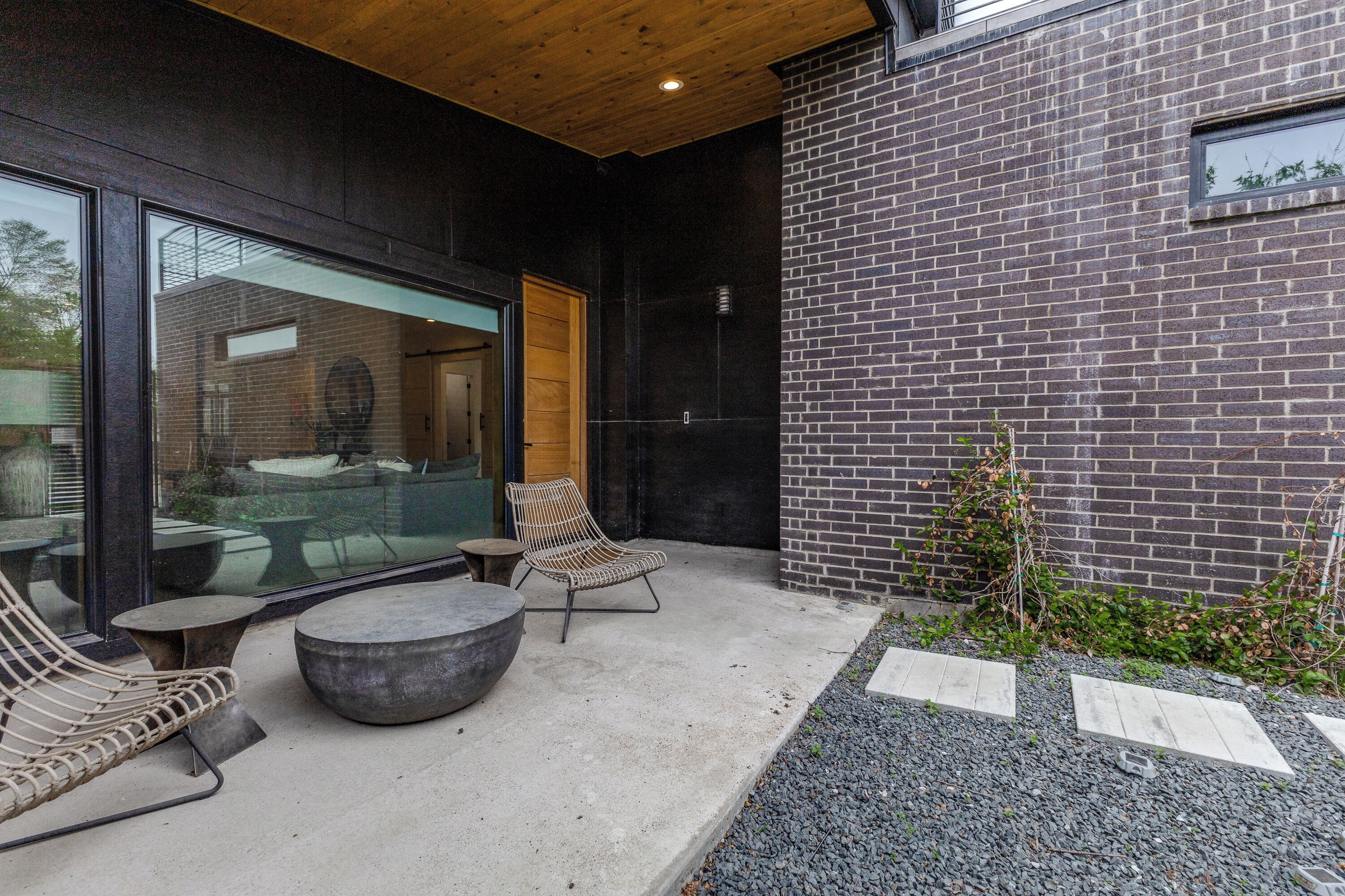 An outdoor patio with a concrete floor, a round table, two chairs, and a large planter.