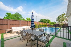A backyard with a pool, outdoor furniture, and a wooden fence. - Modern Serenity: 3 Beds of Calm & Style (Dallas)