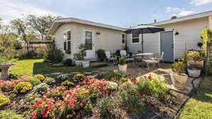 A single-story house with a patio area, outdoor furniture, and a variety of potted plants. - Mary’s Mid-Century Modern House- 3-Bed Haven (Fort Worth)
