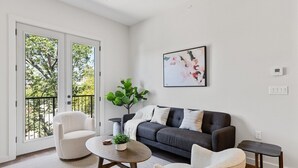 Uma sala de estar moderna com um sofá cinzento, duas poltronas, uma mesa de centro e um vaso com planta.