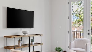 Ein modernes Wohnzimmer mit Flachbildfernseher, zwei Sesseln, einem Couchtisch und einem Deckenventilator.