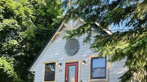 A two-story house with a red door, a small porch, and a staircase leading to the entrance. - Your Downtown Oasis 14-foot ceilings, luxury living. Relaxing outdoor spaces (Elora)